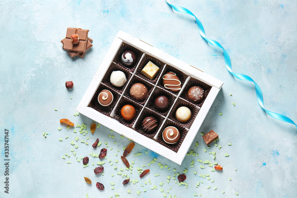 Box with delicious chocolate candies on color background