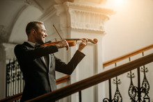 Talented Professional Caucasian Male Violinist Play In The Hall, Practice Before Performance. Classical Music Concept. Man In Suit Perform Music Using Violin