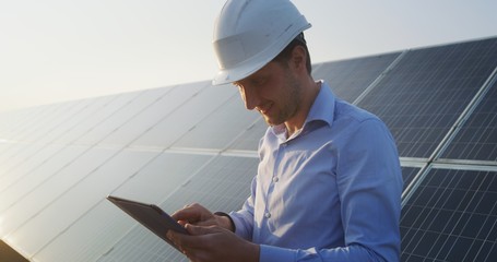 Wall Mural - an young engineer is checking with tablet an operation of sun and cleanliness on field of photovolta
