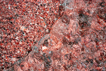 Reflection in the water of a stone texture in the light of the sun. Waves at sea and natural stones. Different colors and a unique pattern of sea waves on a sunny day.