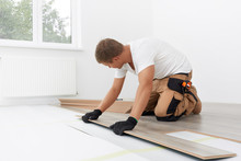 Male Worker Installing Laminate Flooring. Longitudinal Lock Joint - The Sequence Of Technological Methods For Laying And Installation Of Floating Flooring - Laminate - Professional Work