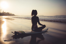 Surfer Woman Meditation On The Surfboard Beach At Sunrise