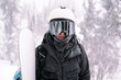 © Annatamila - Portrait of snowboarder with board wearing mask in snowy winter landscape outdoors