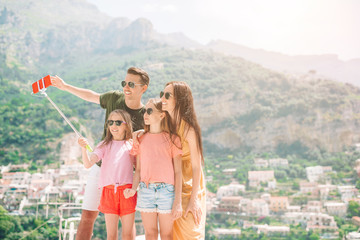 Parents and kids taking selfie photo background Positano town in Itali on Amalfi coast