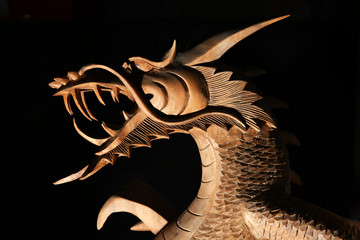 Wall Mural - brown wooden oriental dragon with open mouth on a black background