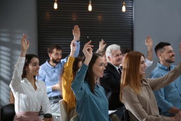 Canvas Print - People raising hands to ask questions at seminar in office