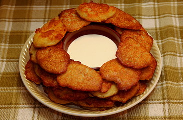 Homemade traditional potato pancakes, served with sour cream, top view.