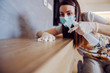 Woman cleaning shelf with antibacterial wipe and sanitizing agent for viruses on home surfaces. Corona virus preventive measures.
