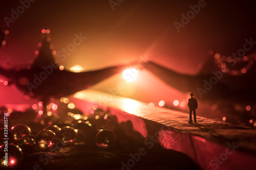Silhouette of a man standing in the middle of the road on a misty night with giant Antique Aladdin arabian nights genie style oil lamp. Creative artwork decoration