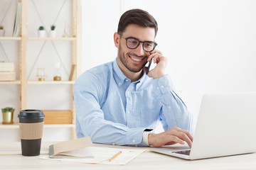 young business man wearing glasses, working in office, looking attentively at screen, typing, answer