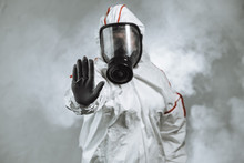 Keep The Distance, Stop To Coronavirus. Disinfector Male In Gas-mask And Protective Suit Disinfect Contaminated Areas Full Of Bacterias. Quarantine Time