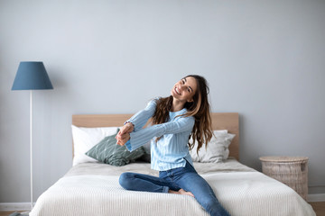 Wall Mural - Young beautiful woman sitting on bed at home.