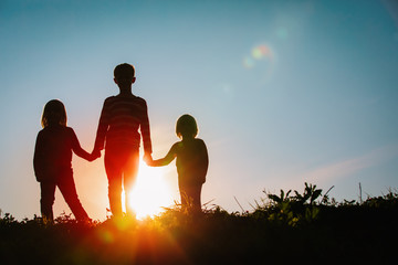 Wall Mural - silhouettes of kids - boy and girls - holding hands at sunset