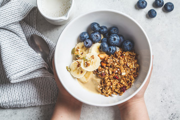 Wall Mural - Granola with berries and fruits in a white bowl in hands. Healthy breakfast concept.