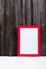 red picture frame, blank copy space, white table, weathered wooden wall