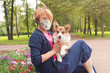 © artmim - Optimistic positive woman in medical mask walking with dog outdoors (60 years old)