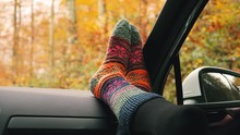 Woman Feet In Warm Colourful Socks On Car Dashboard. Beautiful Autumn Season Roadtrip.