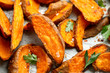 Healthy Baked Orange Sweet Potato wedges with dip sauce, herbs, salt and pepper.