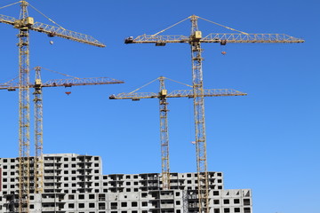 Construction of new buildings by cranes on a sunny day.