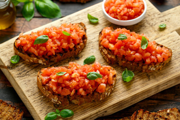 Wall Mural - Tomato bruschetta seasoned with basil on a rustic wooden board