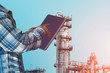 hand holding tablet on oil refinery plant, power plant background