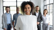 © fizkes - Close up headshot portrait of happy african american businesswoman looking at camera. Different smiling businesspeople standing behind of female company mentor. Leader of multi-ethnic team concept.