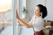 © Seventyfour - Waist up portrait of young Asian woman washing windows while enjoying Spring cleaning in house or apartment, copy space