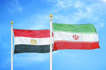 Egypt and Iran two flags on flagpoles and blue cloudy sky