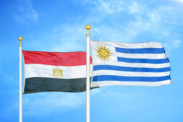 Egypt and Uruguay two flags on flagpoles and blue cloudy sky