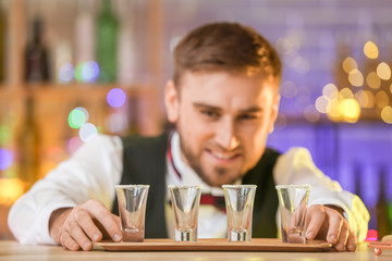 Wall Mural - Handsome male bartender with shots of tequila in pub