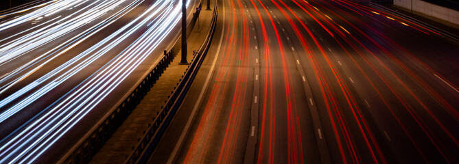 White and red lights of a car in motion at long exposure on a night highway. Background with stripes.