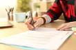 © PheelingsMedia - Student girl hands signing contract on a desk