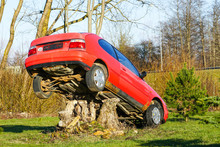 A Red Car Placed On A Large Stump, An Environmental Object