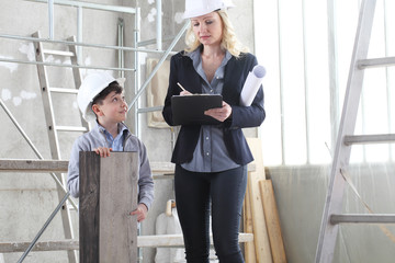 Wall Mural - woman interior designer or architect mom with her son at work, they choose how to furnish the house, inside the construction site