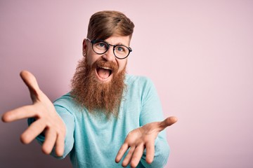 Sticker - Handsome Irish redhead man with beard wearing glasses over pink isolated background smiling cheerful offering hands giving assistance and acceptance.