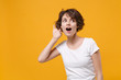 © ViDi Studio - Curious young brunette woman girl in white t-shirt posing isolated on yellow orange wall background studio portrait. People lifestyle concept. Mock up copy space. Try to hear you with hand near ear.