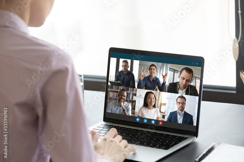 Fotomural Computer monitor view over female shoulder during group video call with multi-ethnic international colleagues or friends