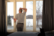 Man In Isolation At Window, With Arm Up