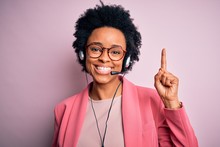 Young African American Call Center Operator Woman With Curly Hair Using Headset Pointing Finger Up With Successful Idea. Exited And Happy. Number One.