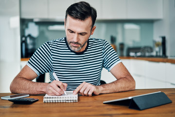 Handsome man at home and calculating home finance