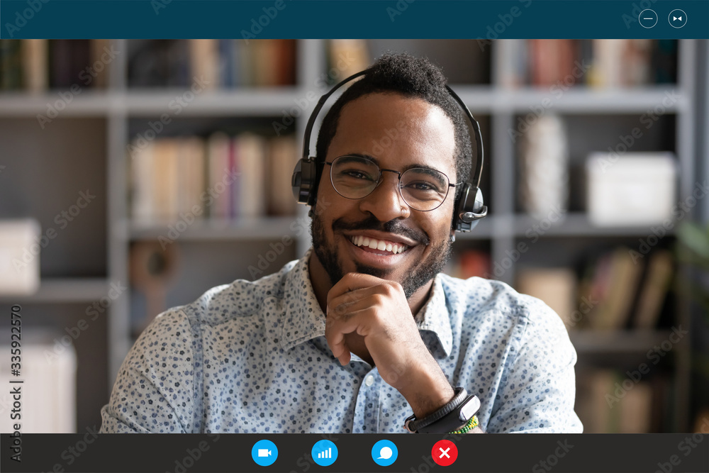 Head shot African man wear headset sit at desk look at cam use videocall conferencing app, pc screen view. Company consultant, teacher portrait, easy e-learn, distant communication with client concept - obrazy, fototapety, plakaty 