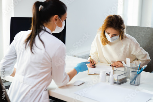 Fotografía Caucasian mother in medical mask writng permission on treatment