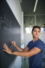 students in a classroom - handsome student solving a math problem on a blackboard during math class