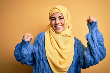 Poster - Young beautiful brunette muslim woman wearing arab hijab over isolated yellow background Dancing happy and cheerful, smiling moving casual and confident listening to music