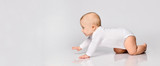 Chubby ginger baby boy in bodysuit, barefoot. He smiling, creeping on floor isolated on white background. Close up, copy space