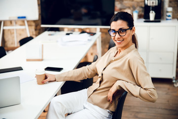 Wall Mural - Beautiful young woman sitting at the table in office