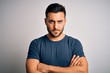 © Krakenimages.com - Young handsome man wearing casual t-shirt standing over isolated white background skeptic and nervous, disapproving expression on face with crossed arms. Negative person.