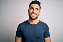 Young Handsome Man Wearing Casual T-shirt Standing Over Isolated White Background Looking Away To Side With Smile On Face, Natural Expression. Laughing Confident.