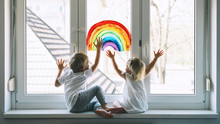 Little Children On Background Of Painting Rainbow On Window