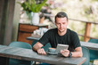 © travnikovstudio - Young man with laptop in outdoor cafe drinking coffee.